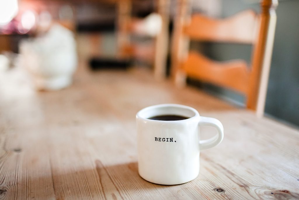 Teetasse mit der Aufschrift "Begin" auf einem Tisch